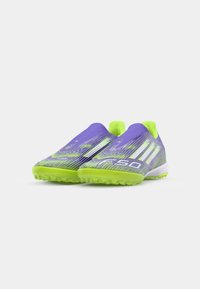 Purple and green athletic shoes with a sleek design, textured upper, and rubber soles featuring traction studs. Includes three white stripes.
