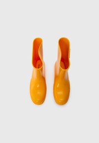 Bottes en caoutchouc jaune avec une finition brillante, bout arrondi et ouverture large. L'intérieur présente une touche d'orange vif. Pas de matériel visible.