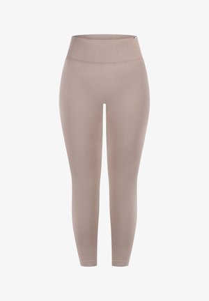 Beżowe legginsy mają wysoki, prążkowany pasek i gładki, elastyczny materiał, który dopasowuje się do nóg, sięgając tuż nad kostki.
