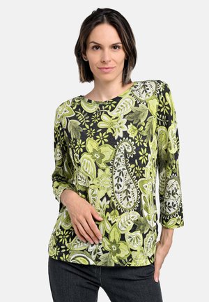 Mehrfarbiger langärmeliger Oberteil mit schwarzem Grund und grünen Blumen- und Paisleymustern. Der Stoff wirkt weich und hat einen lockeren Schnitt.