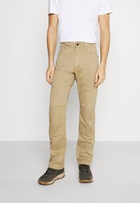 Khaki cargobyxor i slitstark tyg, med rak passform, flera fickor och synliga sömnadsdetaljer. Kombinerade med vandringsskor.