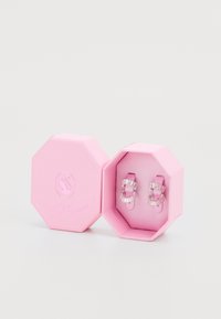 Achtkantige rosa Box mit einer strukturierten Oberfläche, die silberne Creolen mit rechteckigen klaren Steinen enthält.