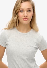 Lys grå ribbet t-shirt med korte ærmer og rund halsudskæring, med et diskret broderet "Superdry" logo på fronten.