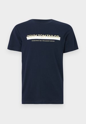 Camiseta de algodón de color azul marino con mangas cortas y cuello redondo. Presenta texto en blanco y dorado: "DENIM TOM TAILOR" y "fundado en dos mil siete."