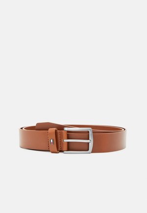 Ceinture en cuir marron avec boucle rectangulaire argentée et petit logo rectangulaire près de la boucle sur un fond clair uni.