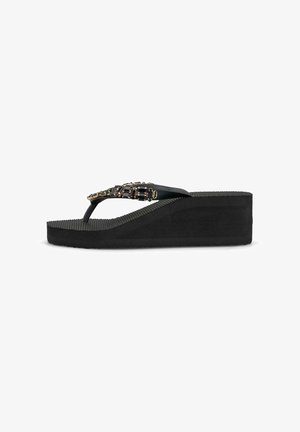 Sandalia de cuña negra con suela texturizada y tira superior decorada con cuentas cuadradas negras y doradas.