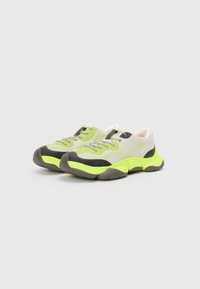 Chunky athletic shoes with a mix of lime green mesh and grey rubber accents. Features rounded shape, contrasting details, and lace-up closure.