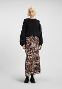 Maglione nero peloso, lunga gonna leopardata con tonalità terra e scarpe platform nere chunky. Cintura semplice che accentua la vita.