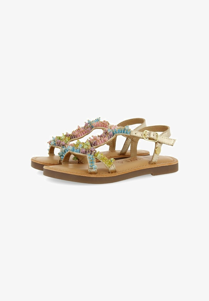 Sandalias planas beige con correas para el tobillo, decoradas con cuentas de colores pastel y pequeños acentos dorados en las correas.