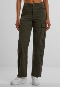 Pantaloni cargo di colore verde oliva, con molteplici tasche, un dettaglio con zip sulla gamba, vita aderente e gamba dritta.