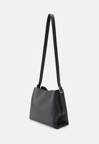 Sac à épaule en cuir noir, doux, avec une seule bandoulière longue et des accessoires en argent. Forme effilée avec un fond plat pour la stabilité.
