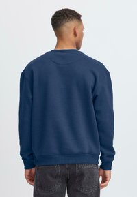 Sudadera azul marino con cuello redondo, puños y dobladillo de canalé. Fabricada con material suave, de corte relajado y con un mínimo de costuras.