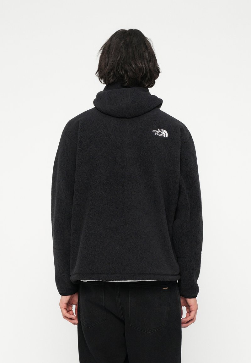 Schwarzer Fleece-Hoodie mit strukturierter Oberfläche, ausgestattet mit einer großen Kapuze und einem kleinen Logo im oberen Rückenbereich. Lässige Passform und gerader Saum.