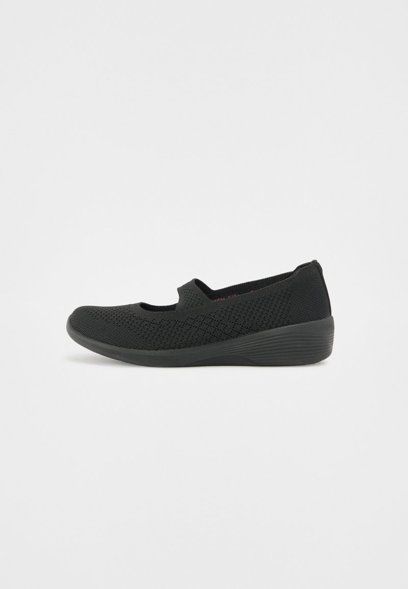 Chaussures noires à enfiler avec une tige en mesh respirant, bout rond et semelle à petit talon. Le design présente un motif texturé sur l'ensemble.
