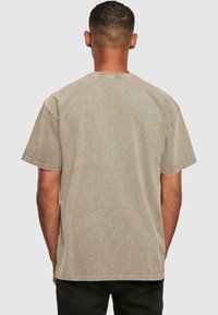 Khaki bomulds-t-shirt med afslappet pasform, korte ærmer og rund halsudskæring, med en subtil tekstur og synlige syninger.