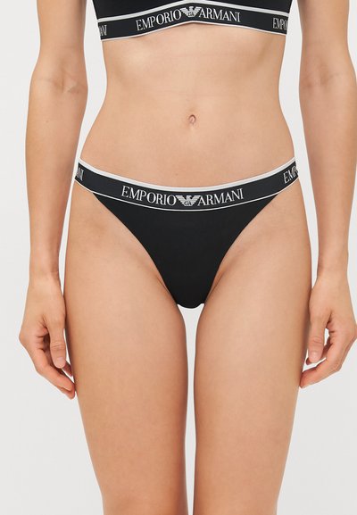 Zwarte stringondergoed gemaakt van gladde stof, met een brede elastische tailleband met het "Emporio Armani" logo en contrasterende strepen.