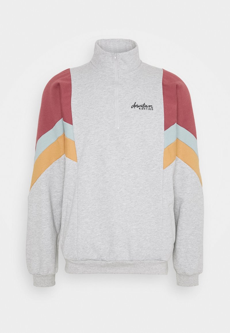 Sudadera gris con cremallera que presenta acentos en bloques de color diagonal en color marón, azul claro y amarillo, y puños acanalados. Logo "dauntless" en el lado izquierdo del pecho.
