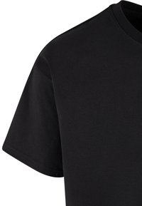 Sort bomulds t-shirt med rund halsudskæring, korte ærmer og en glat tekstur. Syninger synlige langs halsudskæringen og ærmerne.