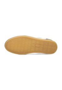 La semelle de la chaussure présente une surface en caoutchouc texturé de couleur beige avec un motif en nid d'abeille et un logo ovale central, conçue pour l'adhérence et la durabilité.