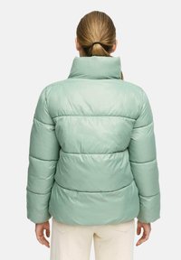 Vadderad jacka i ljus mynta grön, med hög krage, horisontell quiltad design och slät, glansig textur.