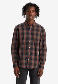 Camisa de cuadros de manga larga en negro, naranja y azul. Presenta un cuello abotonado y un bolsillo en el pecho con el logo. Material de mezcla de algodón.