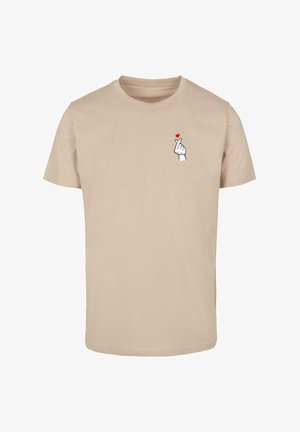 Beige katoenen t-shirt met een gedrukt ontwerp van een hand die een hartgebaar maakt, verfraaid met een klein rood hart boven de vingers.