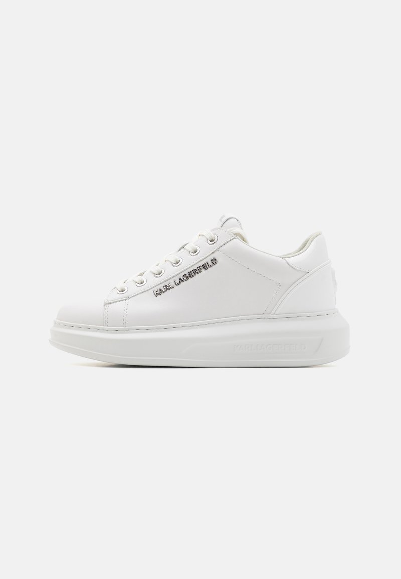 Weiße Leder-Sneaker mit flachen Schnürsenkeln, einer abgerundeten Zehenpartie und einer dicken Sohle. Besondere Merkmale sind ein geprägtes Logo an der Seite und eine glatte Textur.