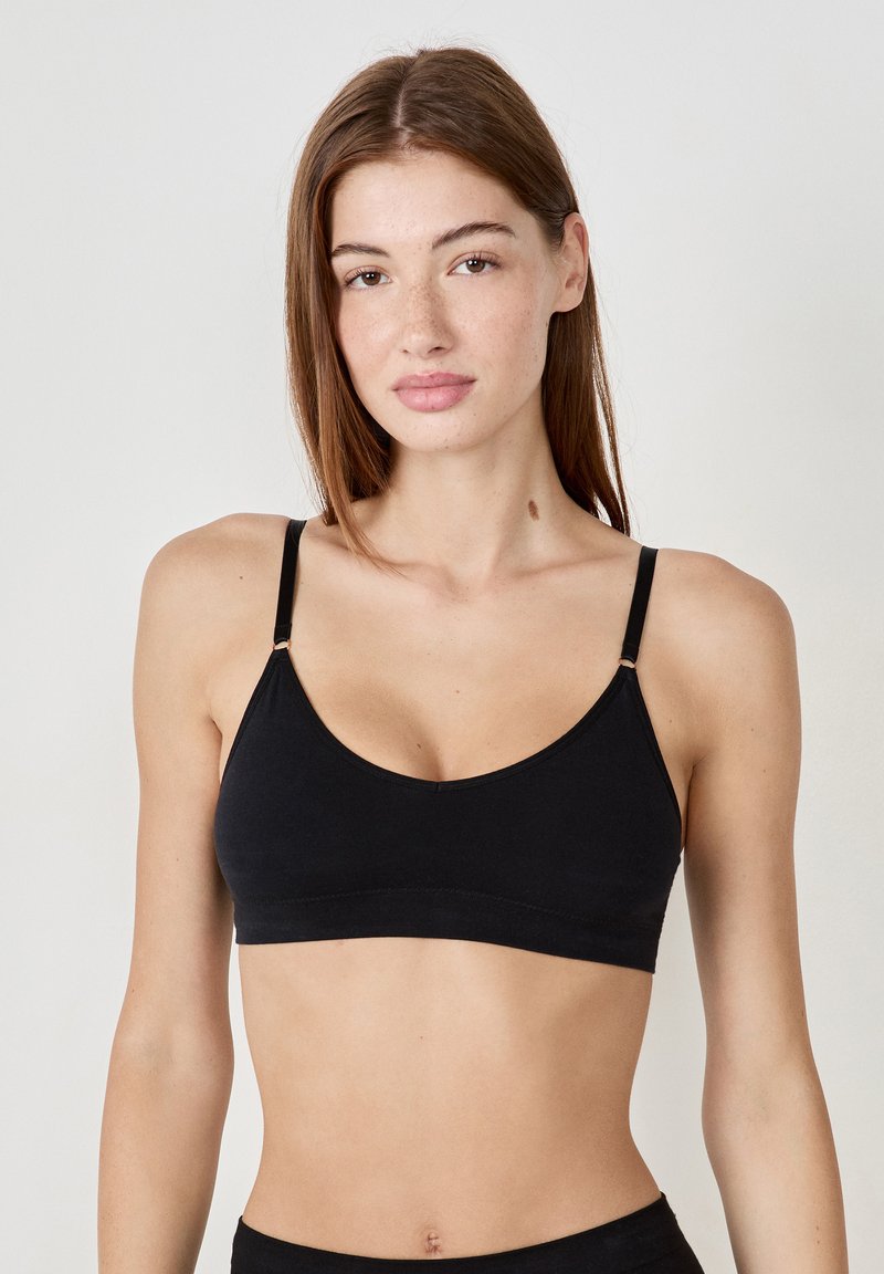 Bralette negro con tirantes finos ajustables, que presenta un escote redondeado y una tela suave. Diseño simple y sin costuras, sin patrones.