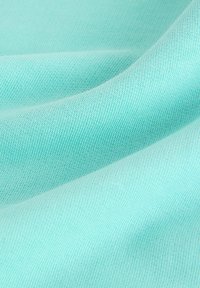 Tissu bleu clair à texture de maille fine montré dans de douces pliures et une lumière douce.