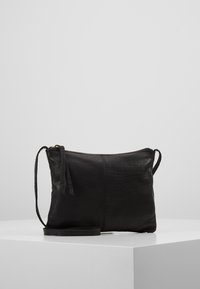 Borsa a tracolla in pelle nera con forma rettangolare piatta, chiusura a zip, tracolla intrecciata e dettagli di cuciture sottili. Texture liscia e design minimale.