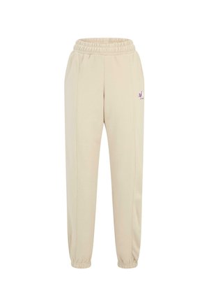 Beige Jogginghosen verfügen über einen elastischen Bund, zulaufende Knöchel, seitliche Nähte und ein kleines lila Logo am linken Hüftbereich.