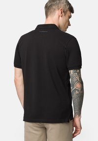 Czarny polo z klasycznym wzorem, krótki rękaw i wyszywane logo z tyłu. Wykonany z oddychającego materiału bawełnianego.