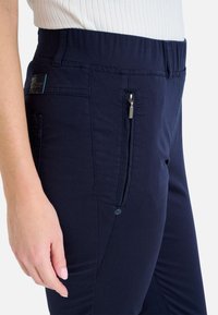 Marineblaue Stretch-Hosen mit elastischem Taillenbund, seitlicher Reißverschlusstasche und strukturierter Oberfläche mit glattem Finish.