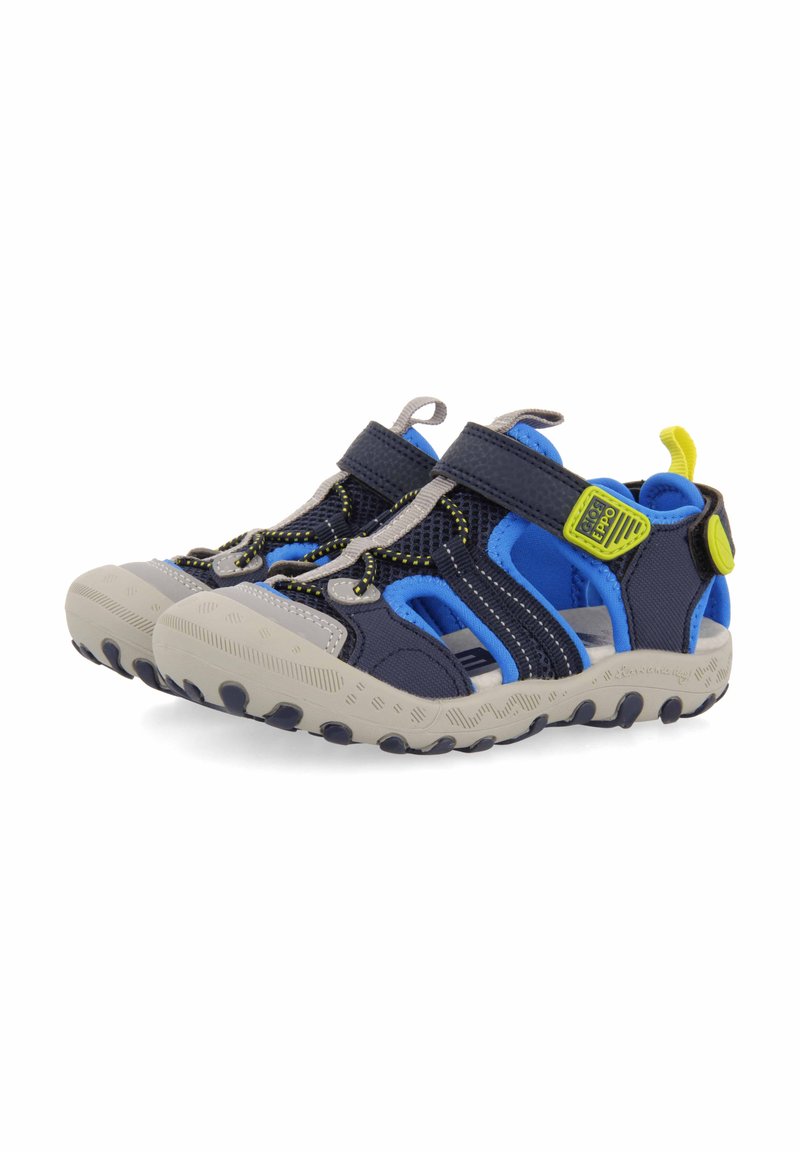 Zapatos de agua azules y marinos con acentos grises, material de malla, correa de velcro y suela de goma texturizada con tracciones distintivas.
