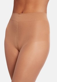 Beige højtaljede sømløse formende shorts lavet af glat, strækbart materiale med en mat overflade, designet til komfort og dækning.