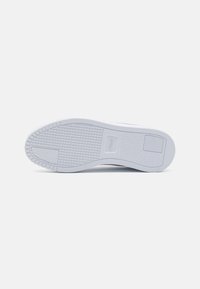 Fehér sneaker talp, strukturált mintával, lapos profilú, kör alakú taposókkal. Enyhén megemelt sarkú.