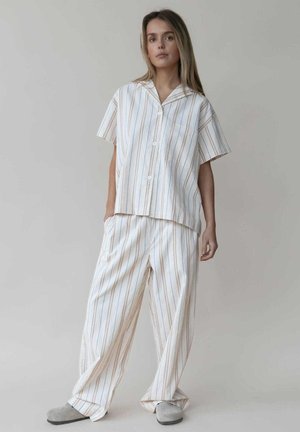 Gestreept loungewear set bestaande uit een kortemouw knoopshirt en wijdvallende broek in wit, blauw en beige tinten met een soepele textuur.