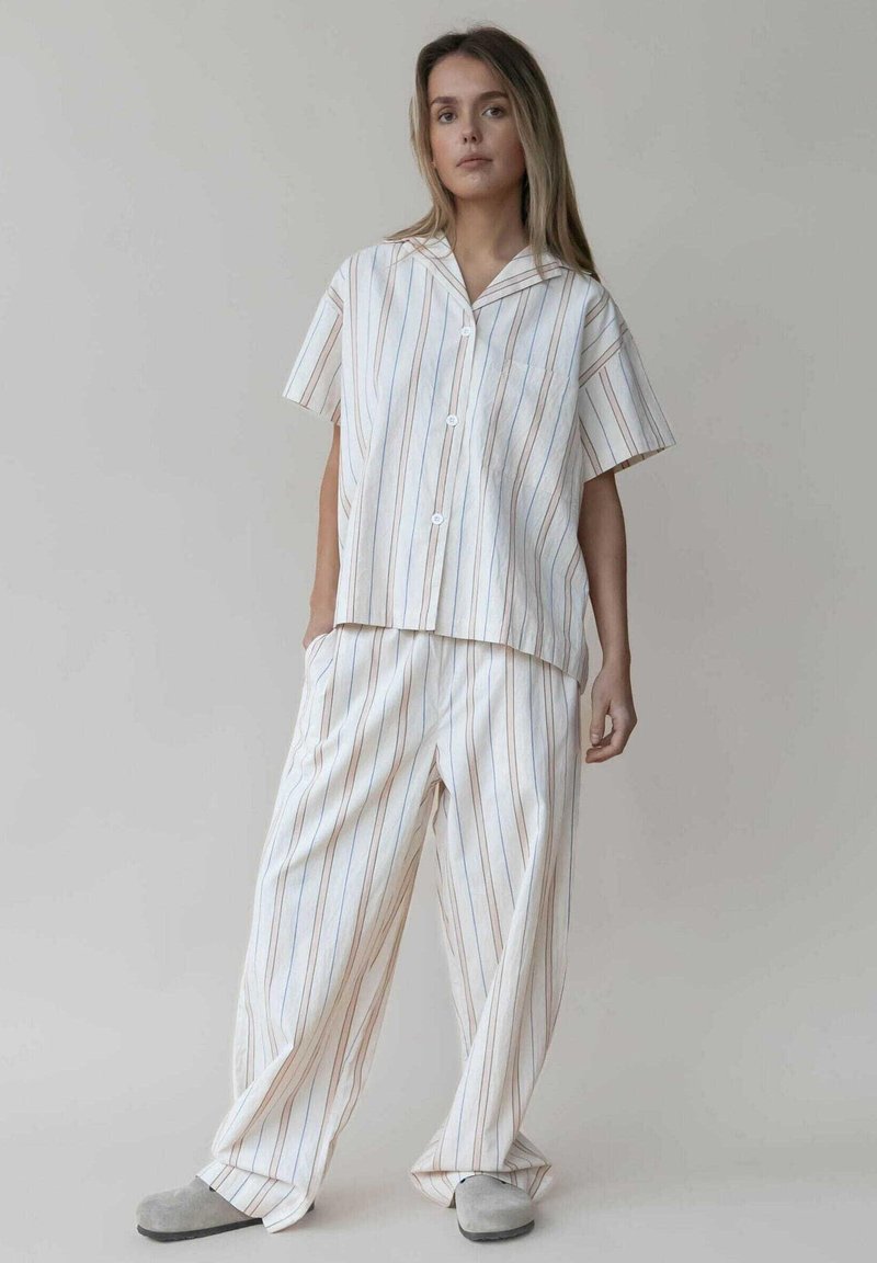 Gestreiftes Loungewear-Set, bestehend aus einem kurzärmeligen Button-Up-Hemd und einer weit geschnittenen Hose in Weiß-, Blau- und Beigetönen mit glatter Textur.