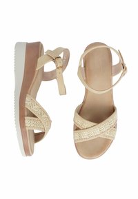 Sandali platform beige con cinturini incrociati caratterizzati da una texture intrecciata. Cinturino alla caviglia regolabile con fibbia dorata. Suola bianca leggera.