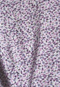 Tissu violet avec un motif dense de petites fleurs blanches et bleu clair et des feuilles noires éparses.