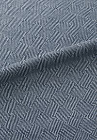 Textile fabric featuring a geometric pattern of small diamonds in navy and light blue tones. Soft texture with a woven appearance.