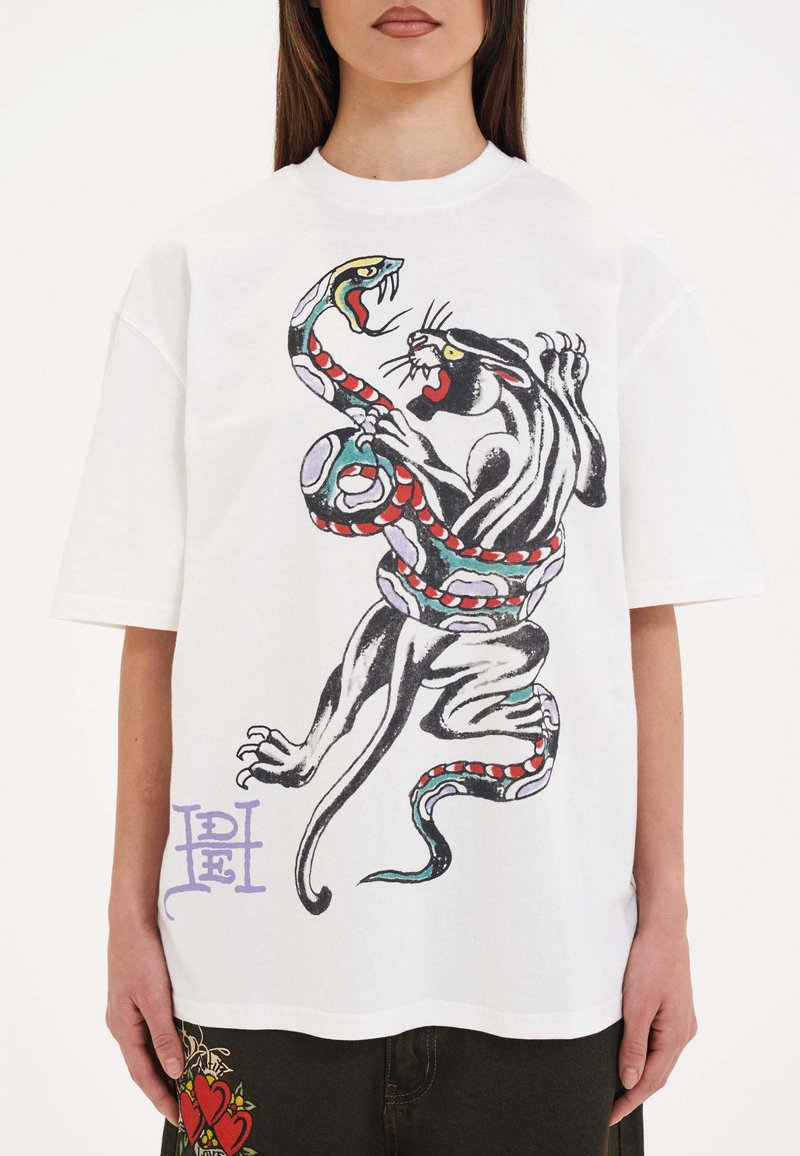 Witte unisex t-shirt met een zwart en rode geïllustreerde panter die verwikkeld is in een kleurrijke slang. Losse pasvorm, ronde hals, korte mouwen.