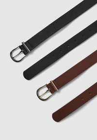 Due cinture in pelle nera e una marrone con fibbie in metallo, distese su una superficie chiara, che mostrano i fori e le texture delle cinghie.