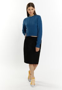 Maglione corto a treccia blu, gonna a tubino nera in suede e sneakers alte gialle. Design semplice e moderno con dettagli testurizzati.