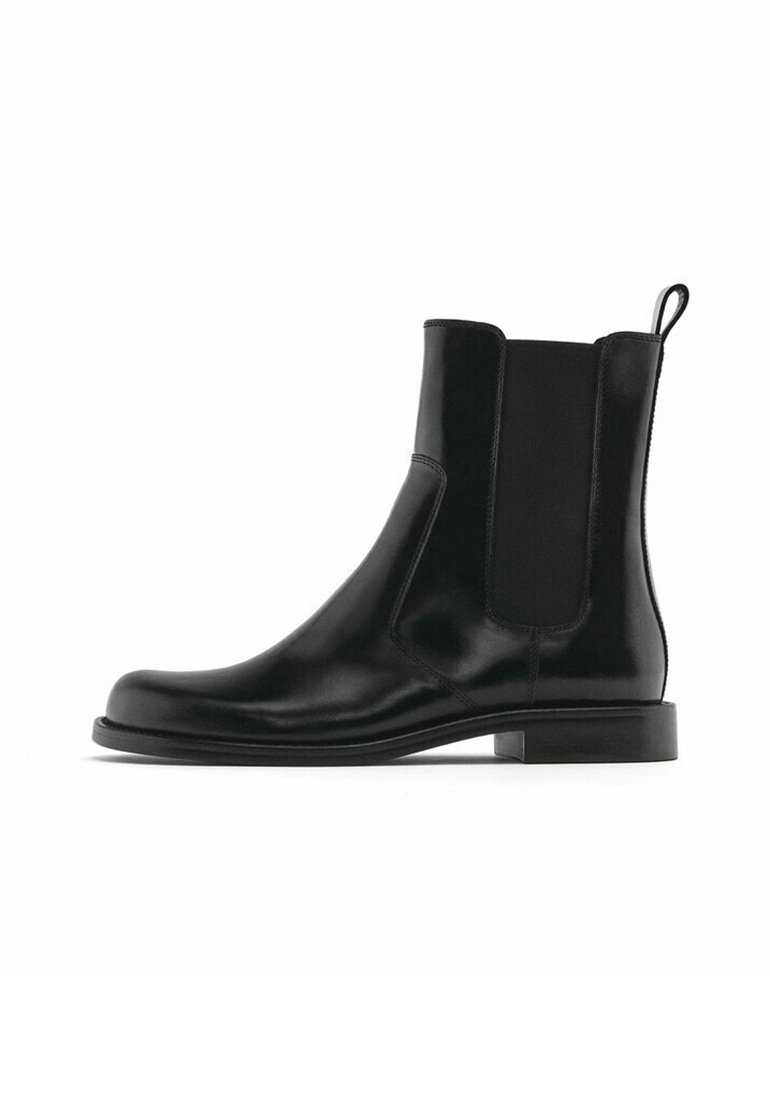 Bottes Chelsea noires en cuir avec panneaux latéraux élastiques, bout arrondi, texture lisse et semelle plate. Dotées d'une languette à l'arrière.