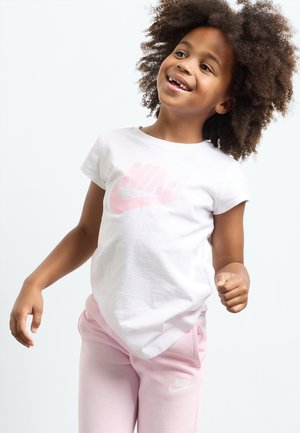 Witte katoenen t-shirt met een roze Nike-logo, gecombineerd met lichtroze joggingbroek met een klein wit Nike-logo, beide in een relaxte pasvorm.