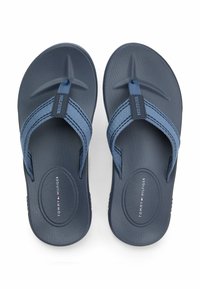 Blå flip-flops med teksturerede såler og blå stofremme, med et logo-tag og et stjernedesign på indersålen.