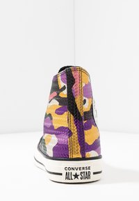 Wysokie sneakersy z wielokolorowym kamuflażem w odcieniach fioletu, żółci, czerni i bieli, z teksturowanym wykończeniem i czarną gumową podeszwą.