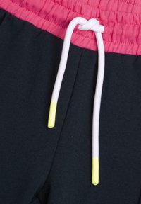 Elastisk midja i rosa med vit snodd och gula tips; mörk marinblått tyg med en slät textur, lämplig för vardagsbruk.