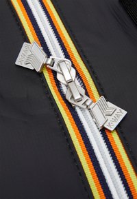 Tissu noir avec une fermeture éclair multicolore comportant des rayures orange, jaune, blanche et marine. Matériel en argent avec le logo "K-Way" visible.